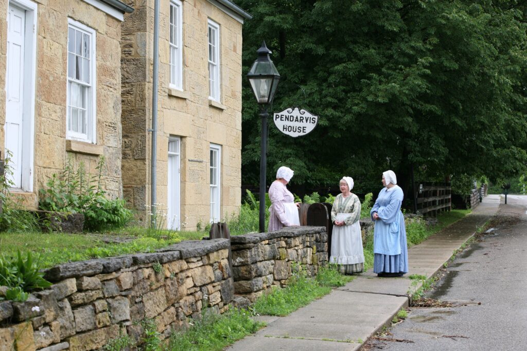 Three women stand around in period clothes are part of their employment at Pendarvis.